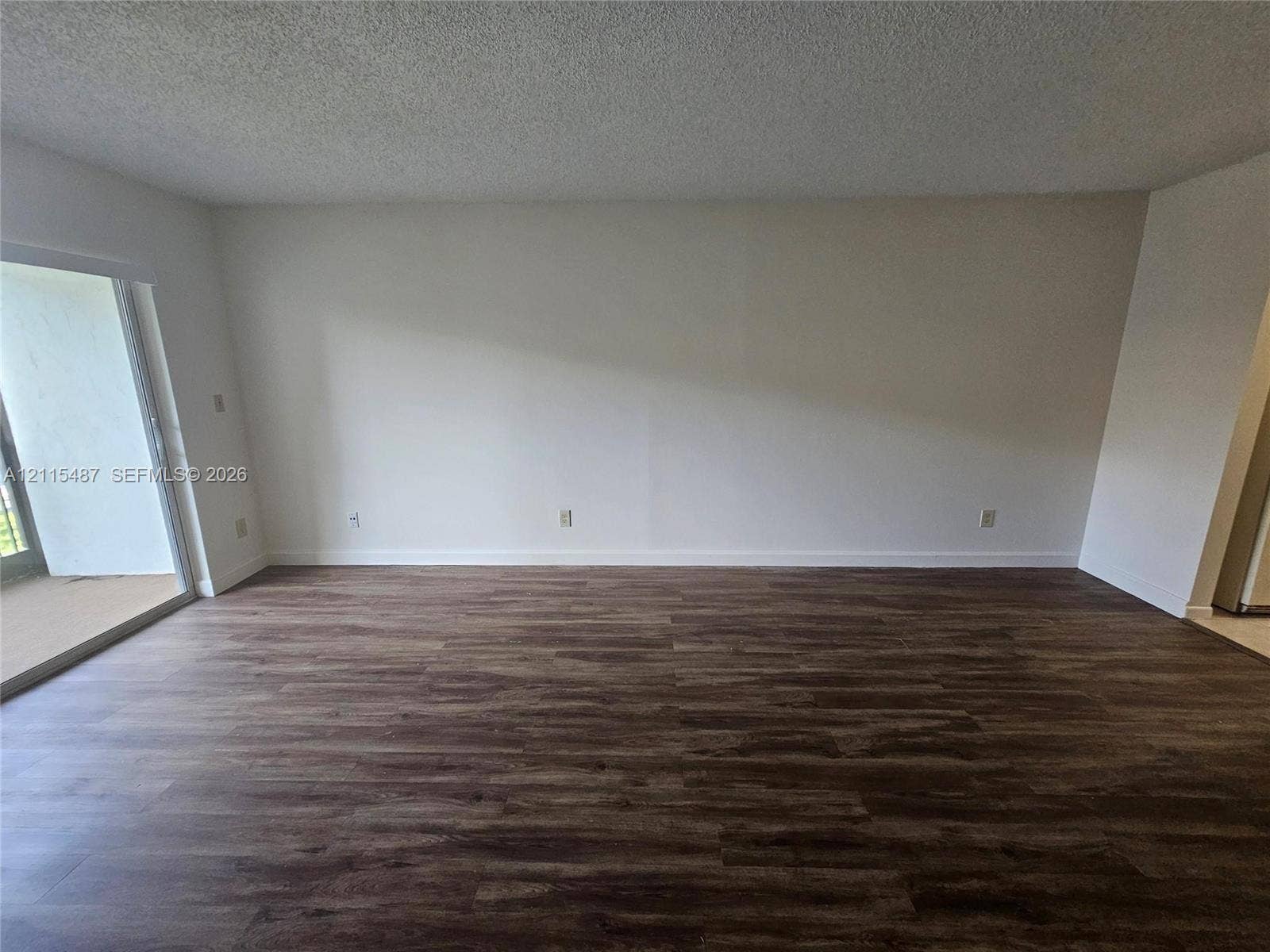 4279 NW 89th Avenue, #205, Coral Springs, Coral Springs, FL 33065 Interior space featuring wood-finish flooring, a sliding glass door, and a textured ceiling