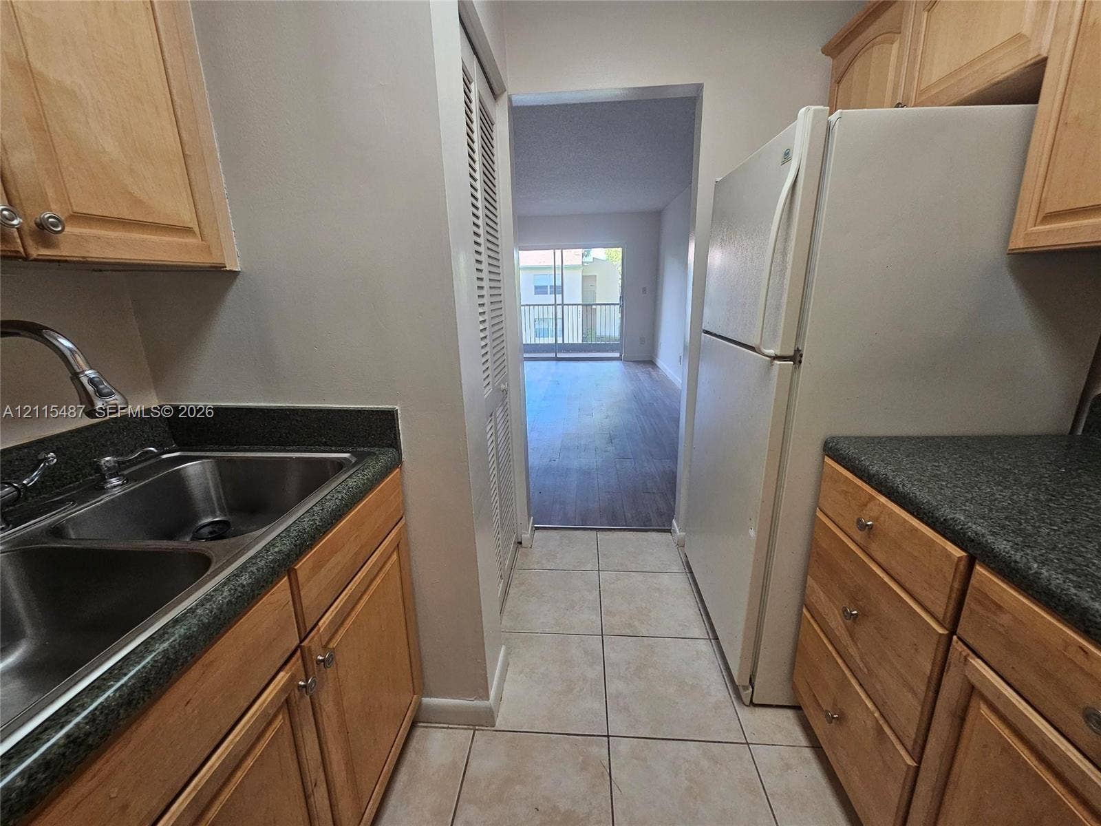 4279 NW 89th Avenue, #205, Coral Springs, Coral Springs, FL 33065 Kitchen featuring natural wood cabinetry, stone-finish countertops, a double-basin stainless steel sink, tiled flooring, and a louvered pantry door