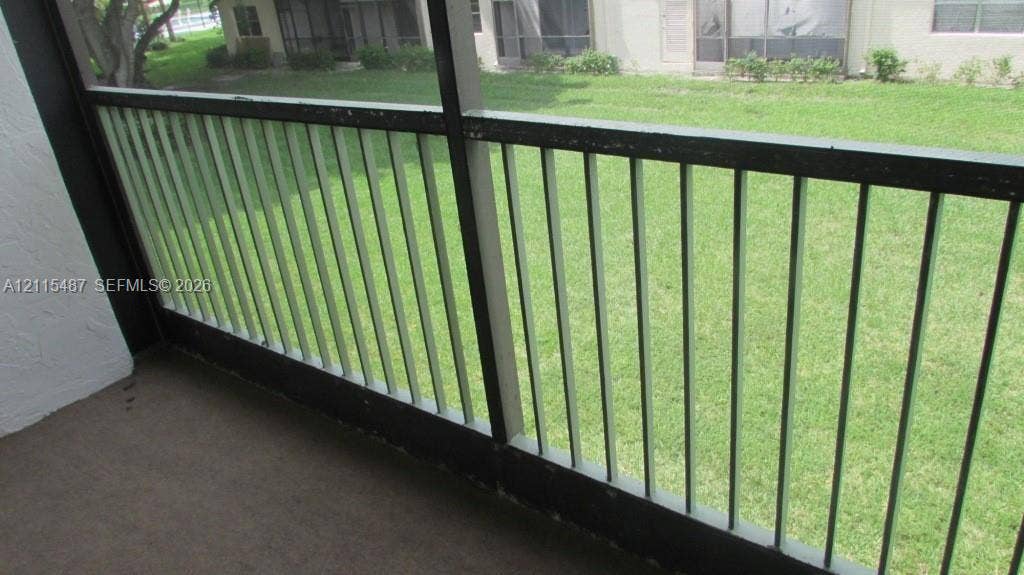 4279 NW 89th Avenue, #205, Coral Springs, Coral Springs, FL 33065 Screen-enclosed balcony featuring a solid surface floor and a vertical metal railing overlooking a grass lawn