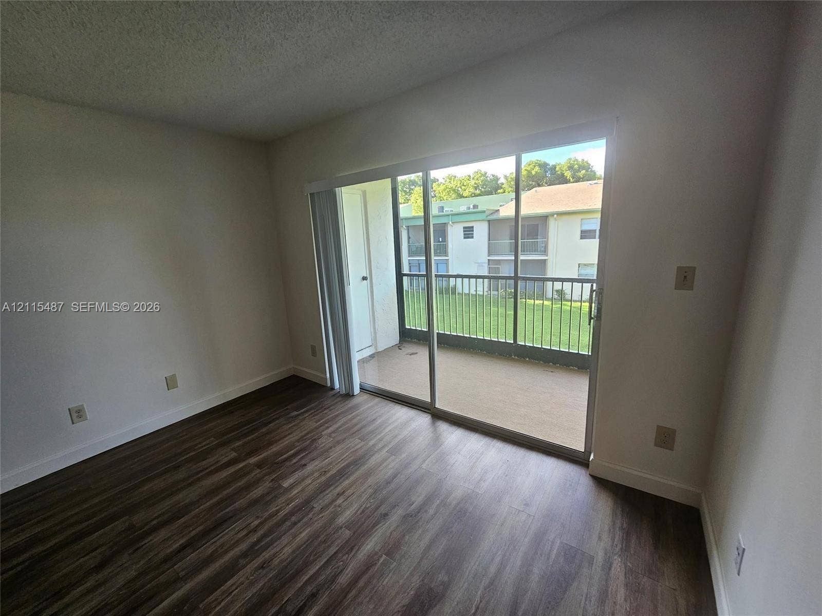 4279 NW 89th Avenue, #205, Coral Springs, Coral Springs, FL 33065 Sliding glass door opening to a private balcony with metal railing and wood-finish flooring