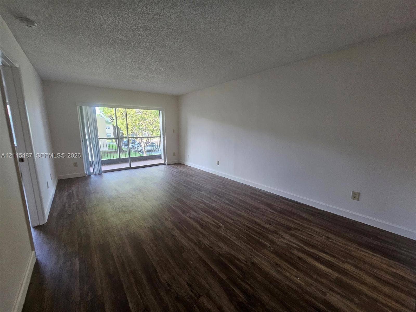 4279 NW 89th Avenue, #205, Coral Springs, Coral Springs, FL 33065 Open living area featuring wood-finish flooring, neutral wall paint, and a sliding glass door providing external access