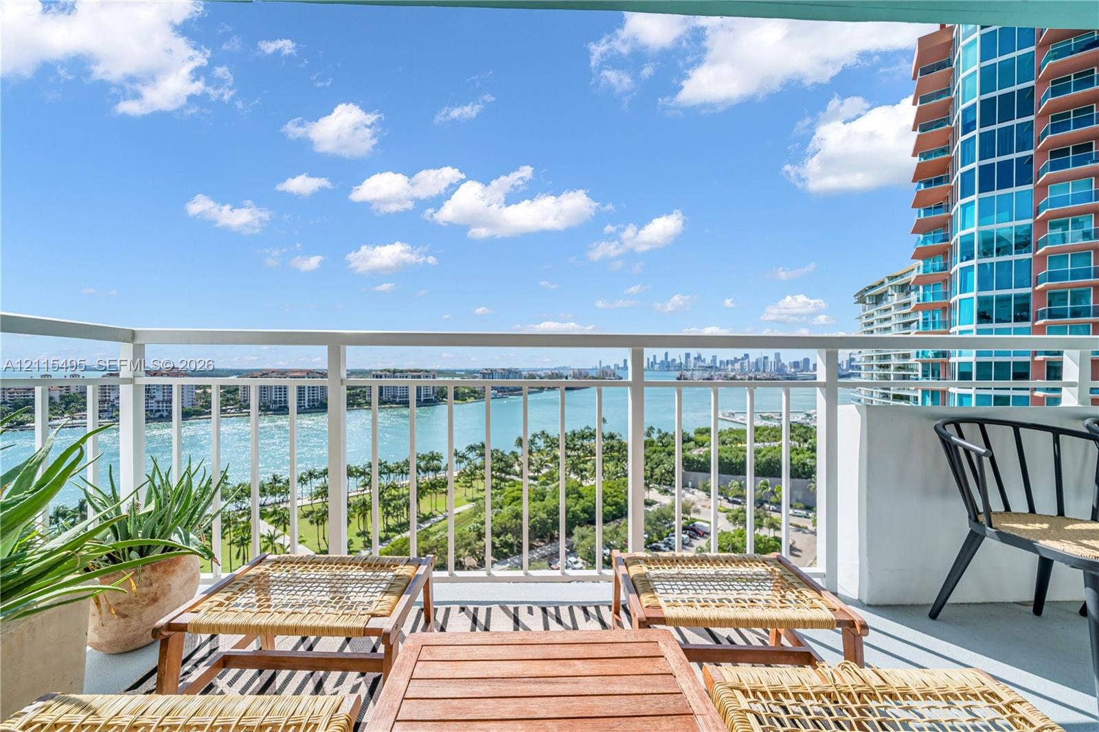 Private balcony featuring white metal railing and open-air access to coastal and urban skyline scenery