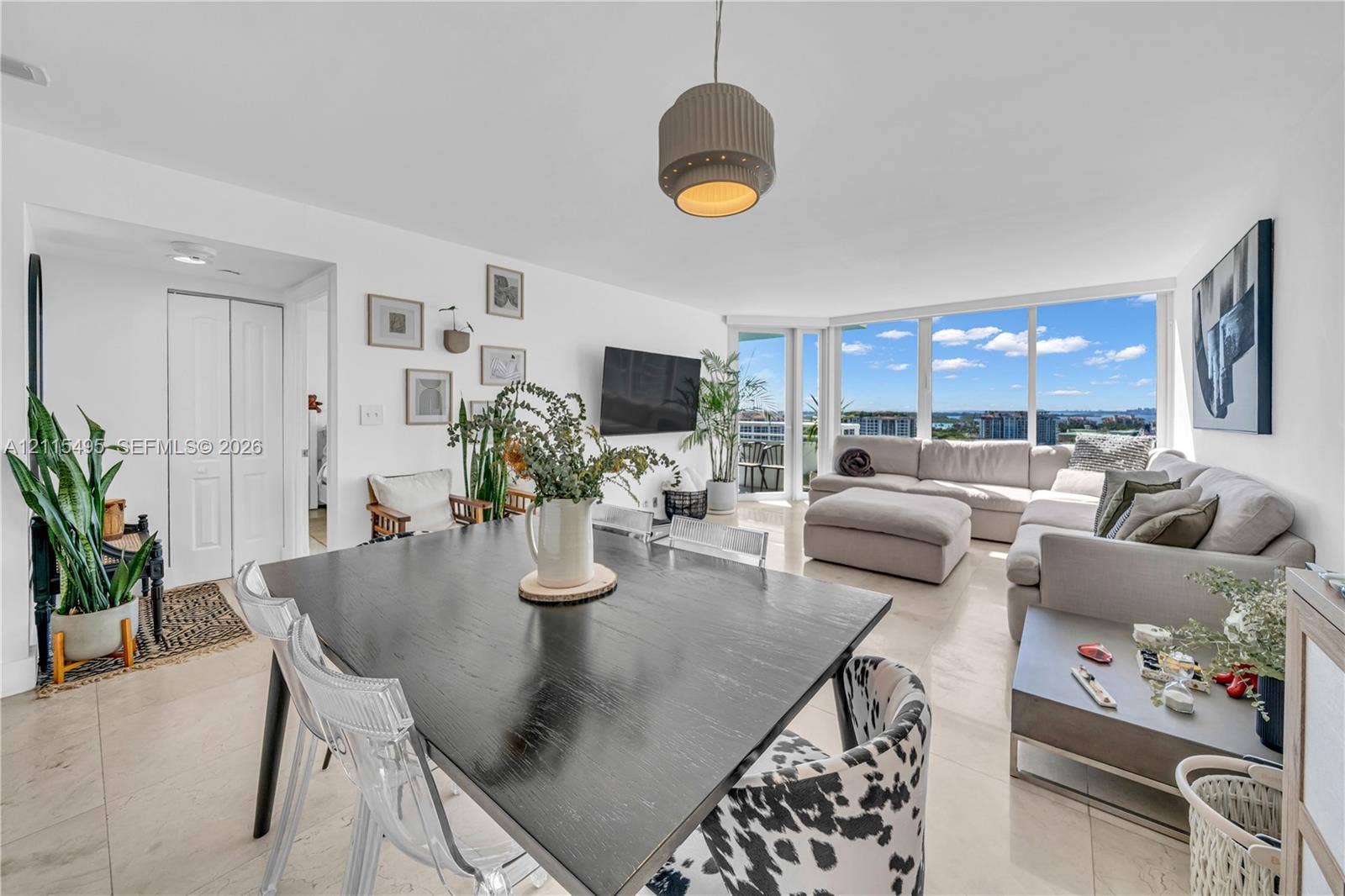 Open-concept interior featuring large-format tile flooring, floor-to-ceiling windows, and a modern drum-style pendant light