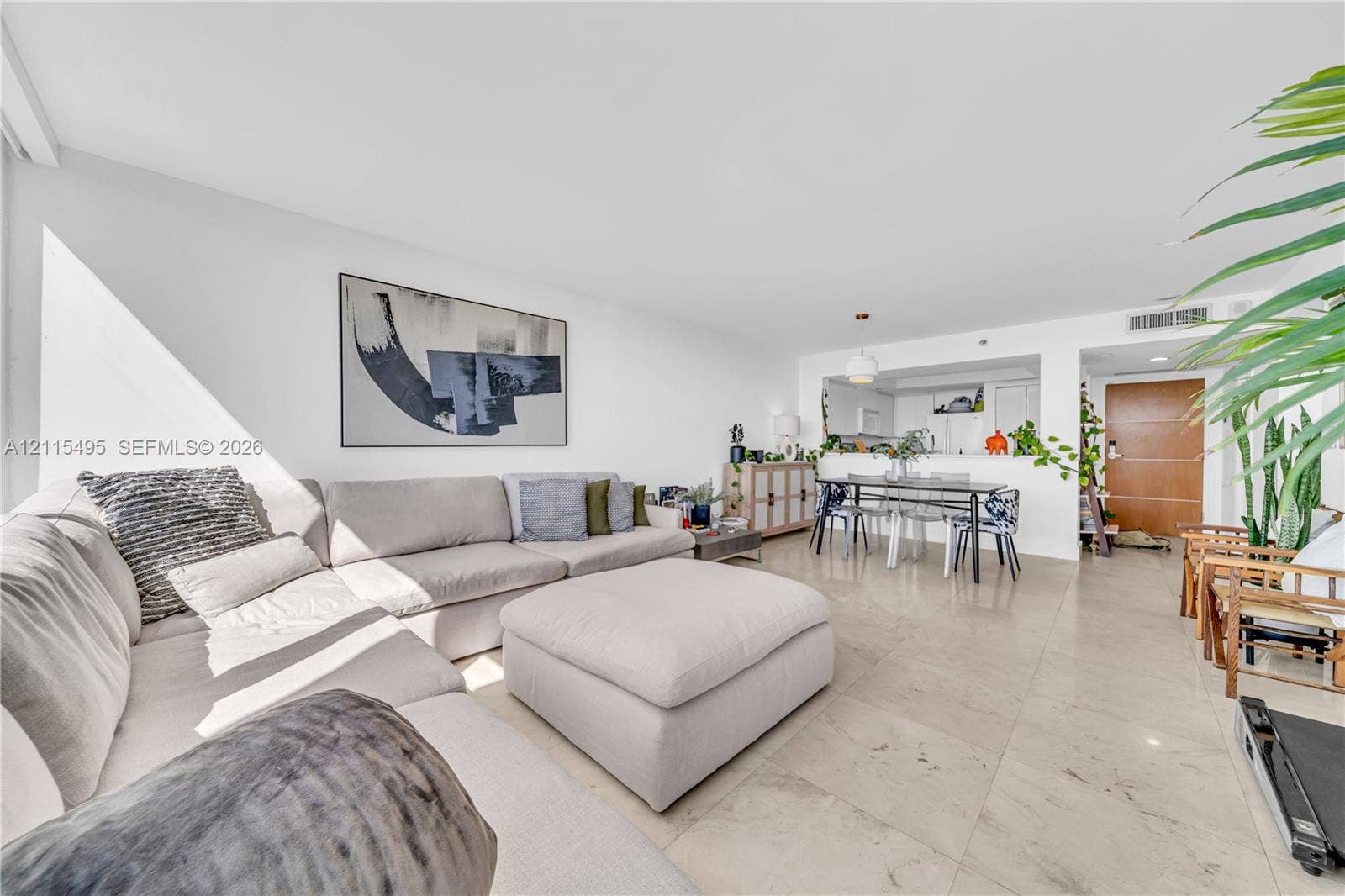 Open-concept interior featuring large-format stone flooring, a pass-through kitchen opening, recessed lighting, and a solid-core wood entry door