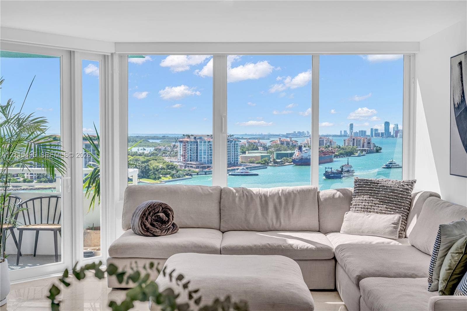 Floor-to-ceiling windows, white-framed glass door, exterior balcony, and expansive water and urban skyline scenery