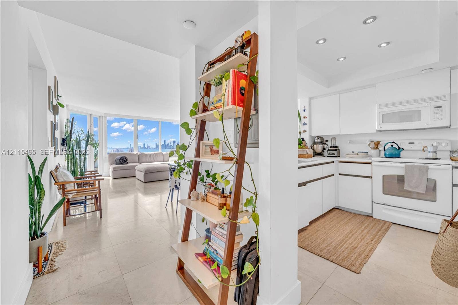 Open-concept living space featuring large-format tile flooring, white cabinetry, integrated recessed lighting, and expansive floor-to-ceiling windows