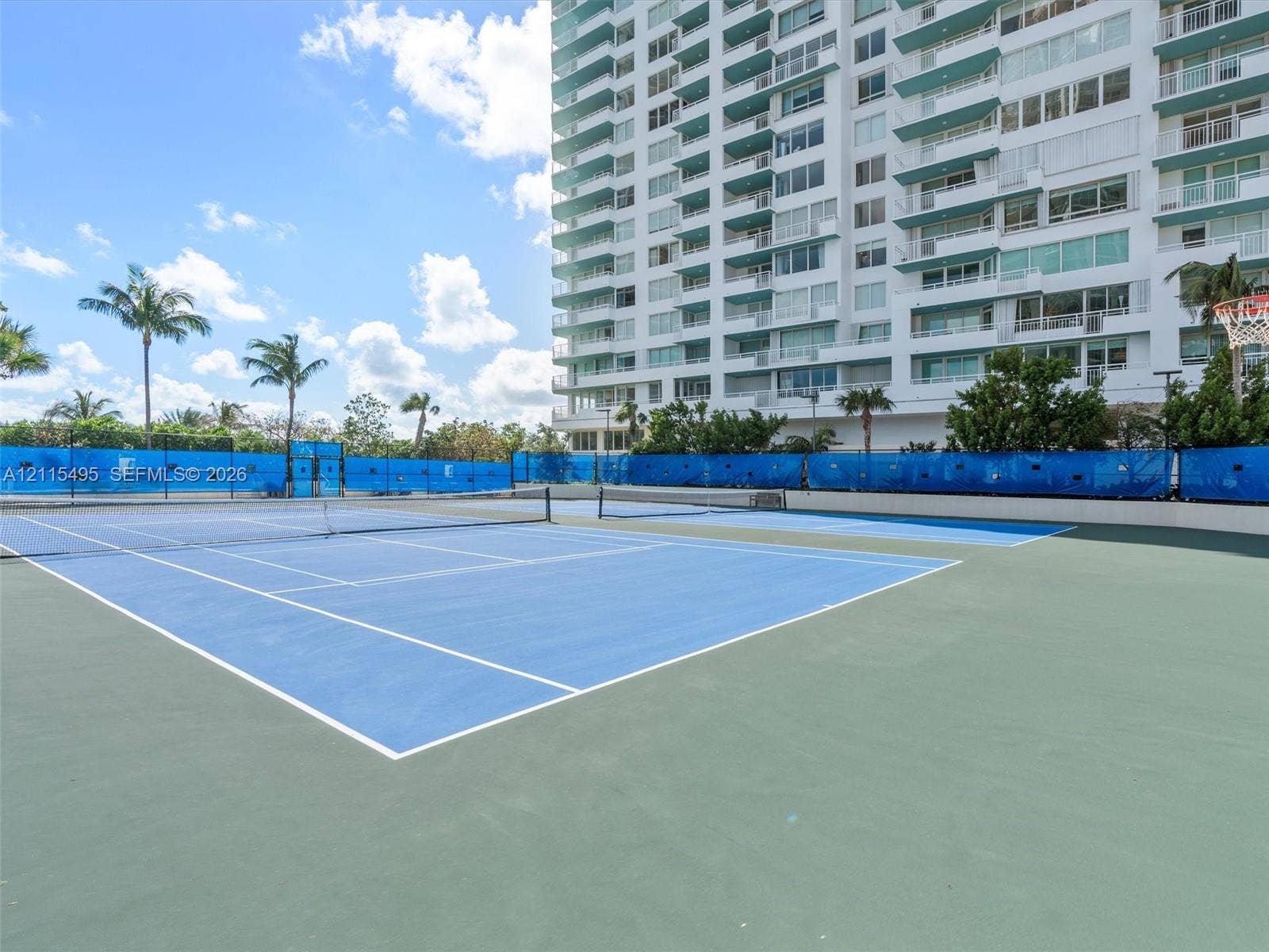 Multi-use recreation area featuring hard-court tennis surfaces and a basketball hoop enclosure