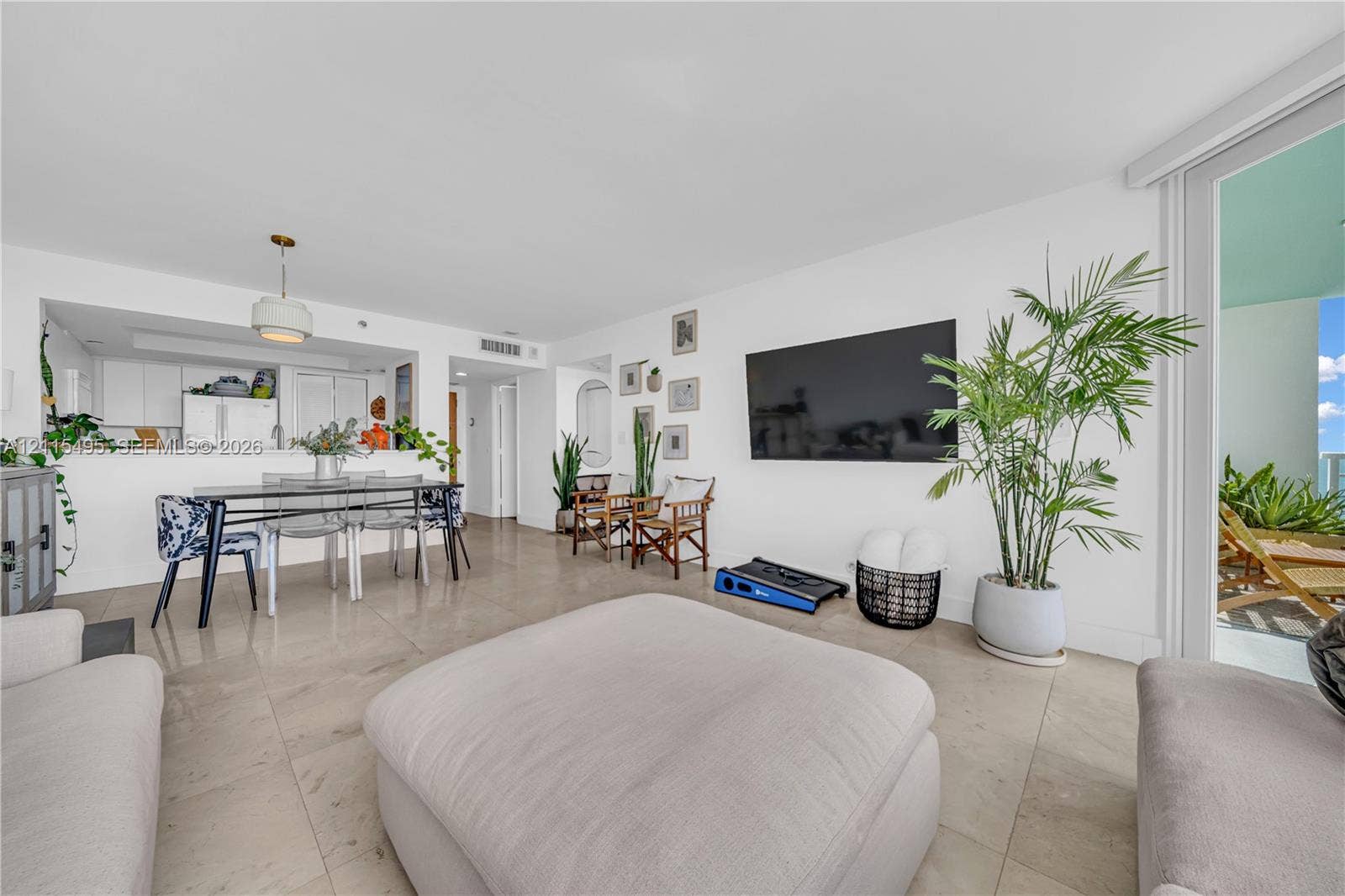 Open-concept floor plan with neutral stone-finish tile flooring, recessed ceiling lighting, a pass-through kitchen window, and sliding glass doors providing outdoor access