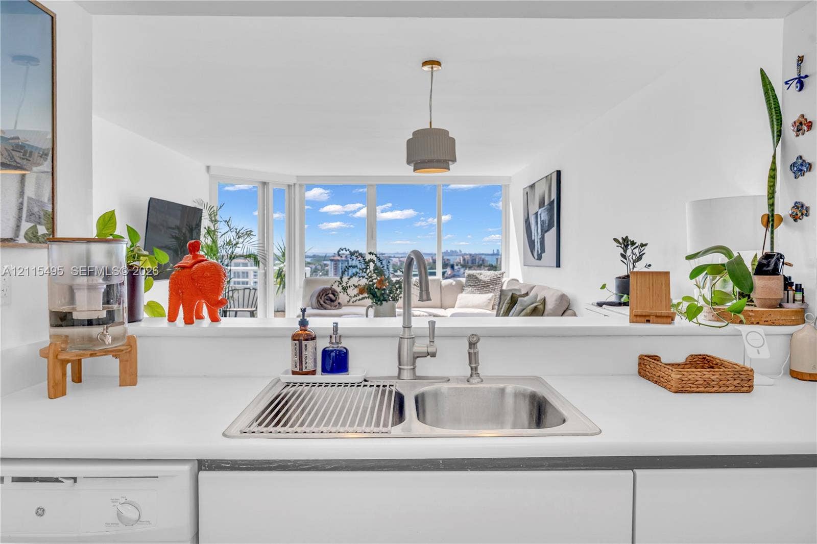 Kitchen featuring a dual-basin stainless steel sink, gooseneck faucet with sprayer, solid surface countertops, flat-panel cabinetry, and floor-to-ceiling windows