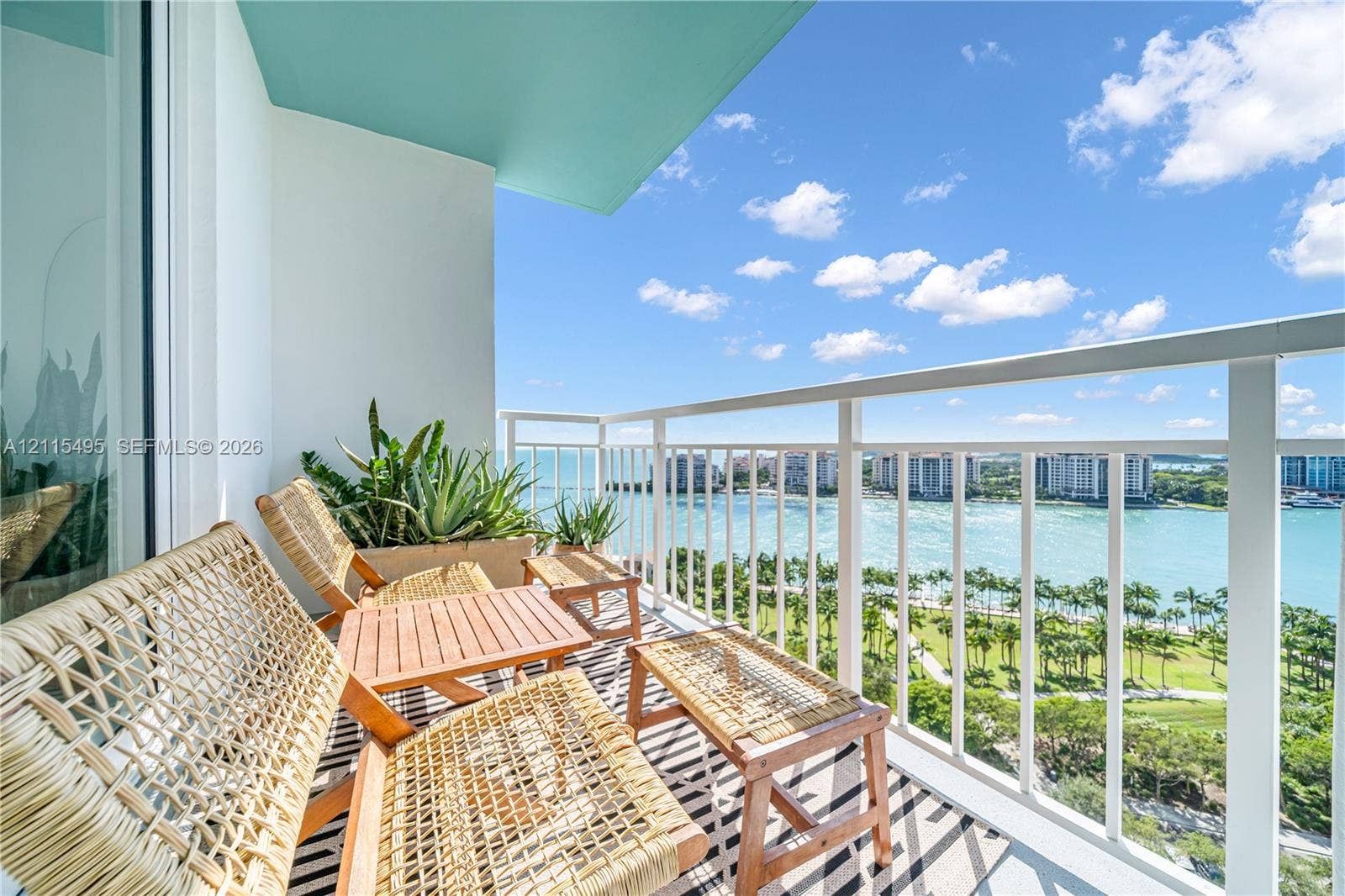 Covered balcony featuring white vertical railings, a teal ceiling finish, and expansive water and landscape surroundings