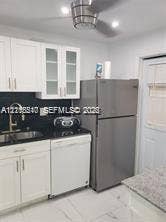 211 NE 8th Avenue, #207, Hallandale Beach, Hallandale Beach, FL 33009 Kitchen featuring white shaker-style cabinetry with glass-panel inserts, stainless steel refrigerator, dark solid-surface countertops, gooseneck faucet, and ceiling-mounted fan