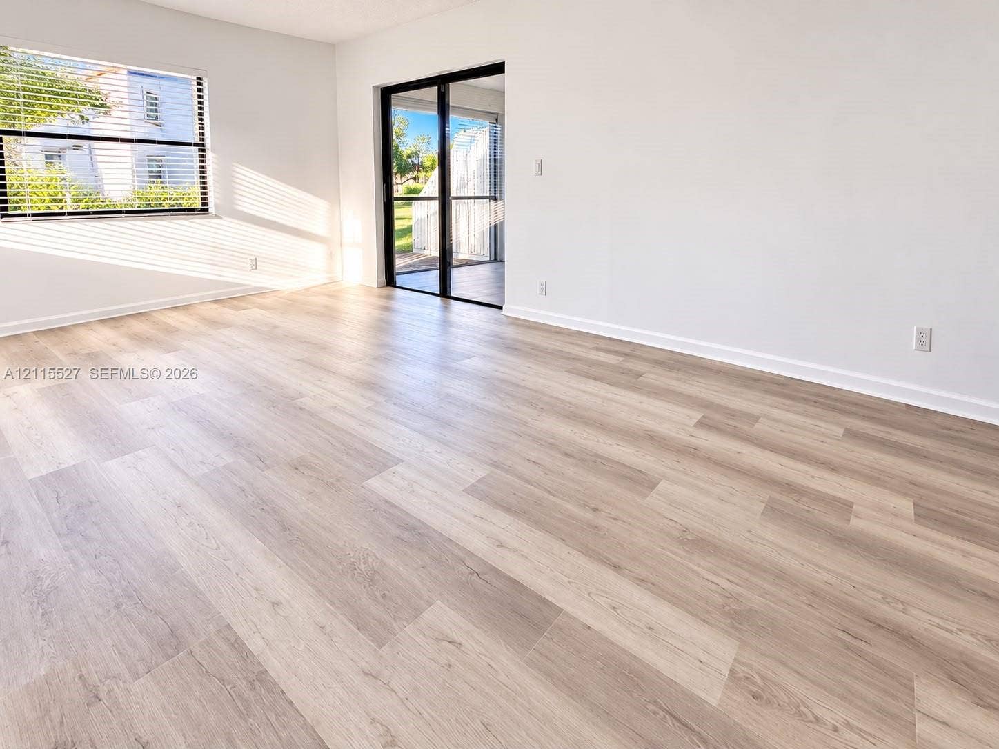 220 Lakeview Drive, #101, Weston, Weston, FL 33326 Interior space featuring light-toned wood-finish flooring, white walls, horizontal window blinds, and black-framed sliding glass doors