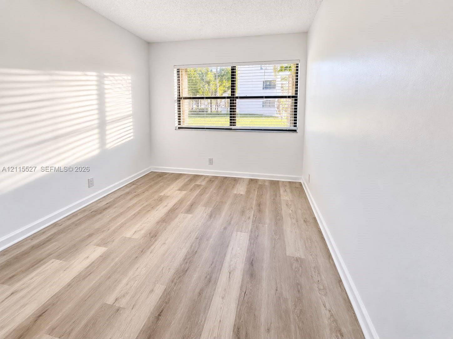 220 Lakeview Drive, #101, Weston, Weston, FL 33326 Neutral interior space featuring wood-finish flooring, a large window, and minimalist white walls