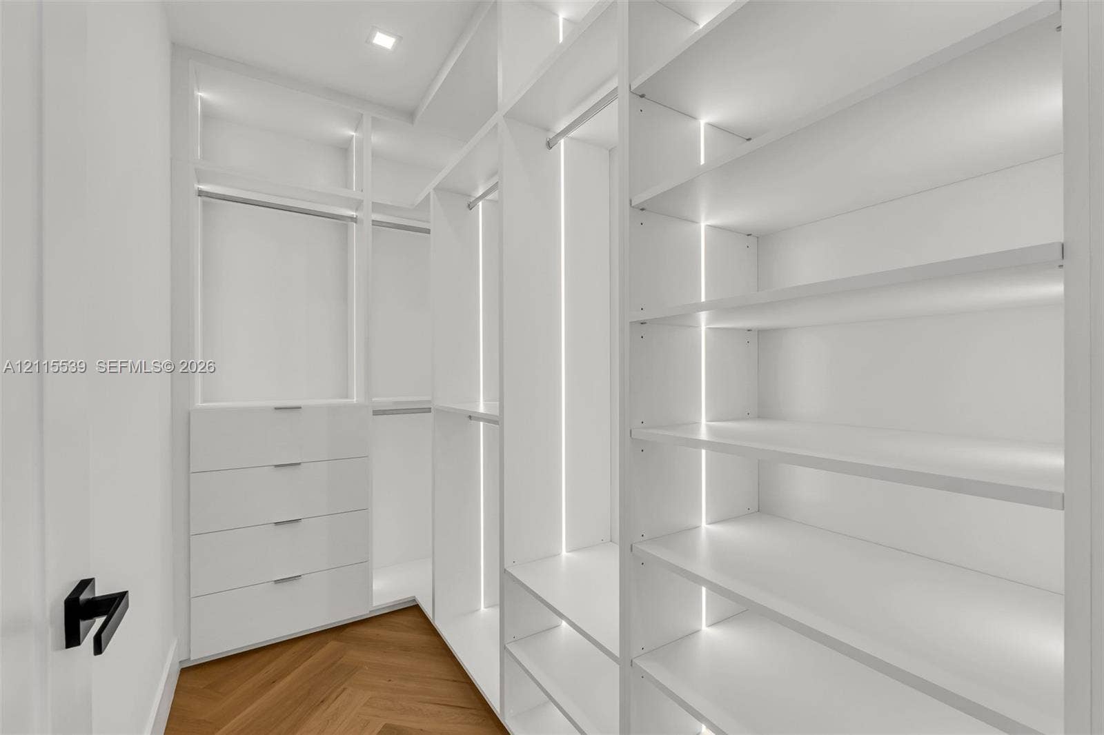 381 SE 6th Terrace, Pompano Beach, FL 33060 Custom storage system featuring floor-to-ceiling white cabinetry, integrated LED strip lighting, built-in drawer units, adjustable shelving, and herringbone wood-finish flooring