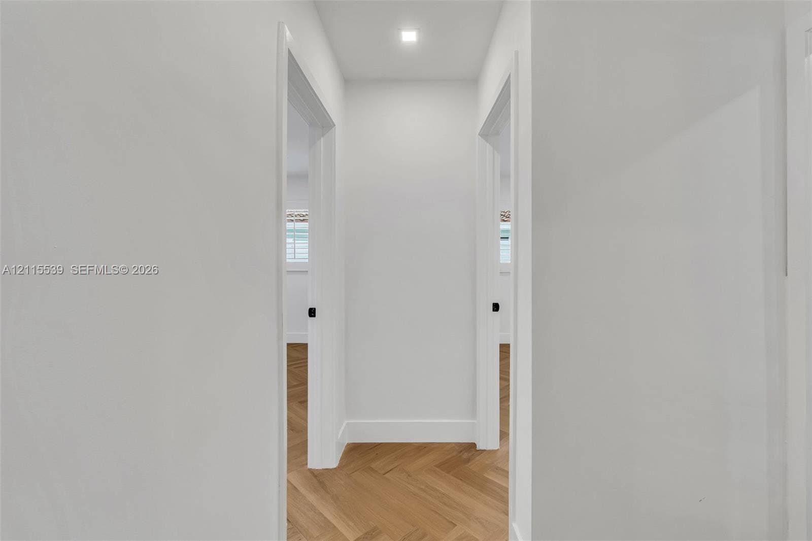 381 SE 6th Terrace, Pompano Beach, FL 33060 Interior hallway featuring light wood-finish flooring in a herringbone pattern, smooth white walls, recessed ceiling lighting, and matte black door hardware