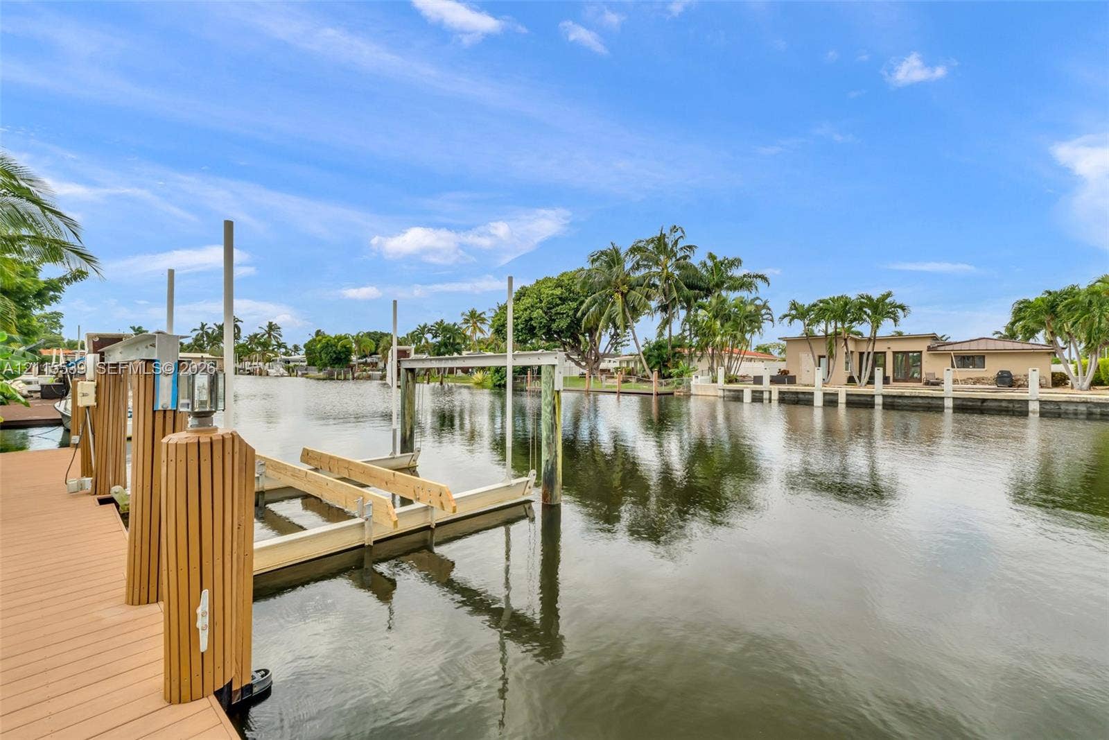 381 SE 6th Terrace, Pompano Beach, FL 33060 Waterfront property featuring a synthetic wood-finish dock, mechanical boat lift, and bulkhead pilings