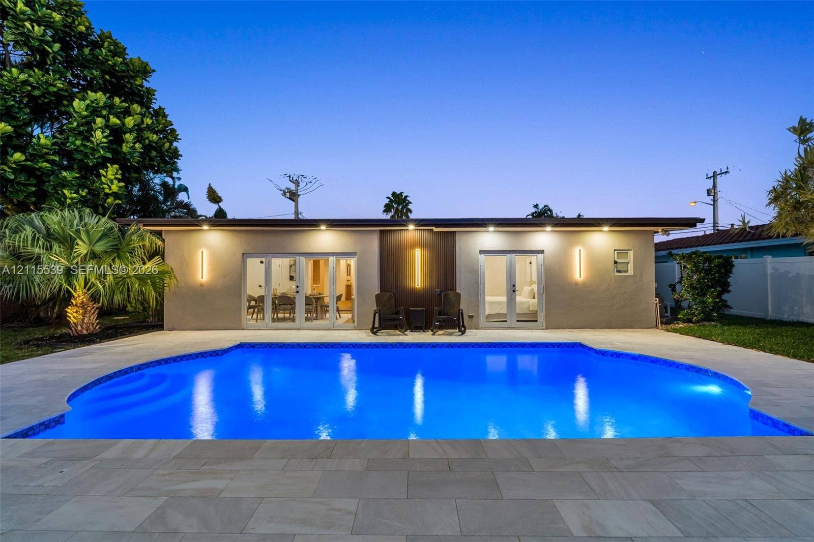 381 SE 6th Terrace, Pompano Beach, FL 33060 Swimming pool with stone-tile decking, dual sets of French doors, recessed ceiling lighting, and vertical exterior wall-mounted fixtures