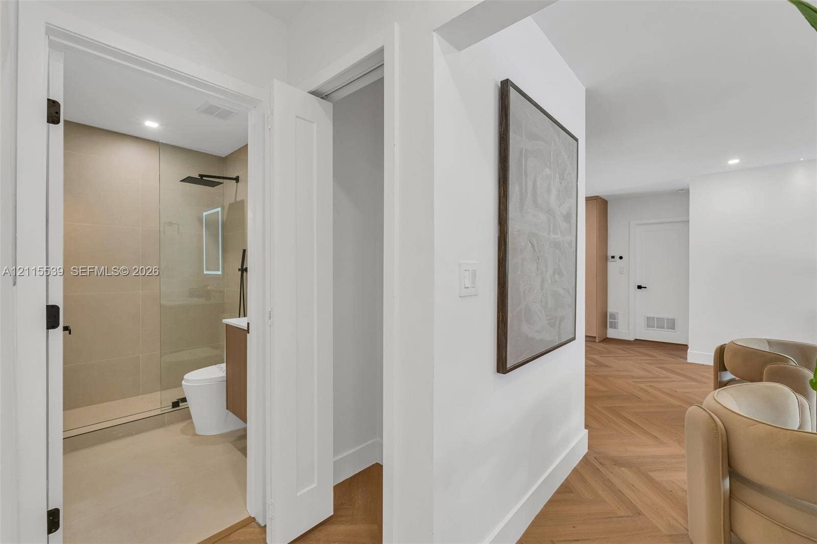 381 SE 6th Terrace, Pompano Beach, FL 33060 Herringbone wood-finish flooring, walk-in shower with large-format tile, frameless glass shower enclosure, matte black rainfall showerhead, and integrated LED bathroom mirror