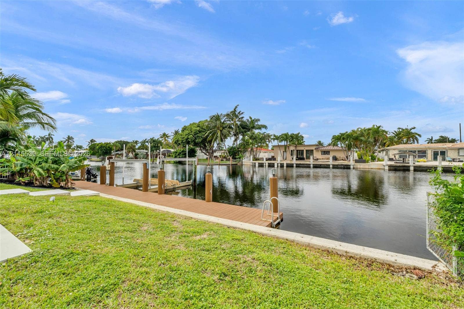 381 SE 6th Terrace, Pompano Beach, FL 33060 Waterfront property featuring a synthetic wood-plank dock, concrete seawall, and private boat lift