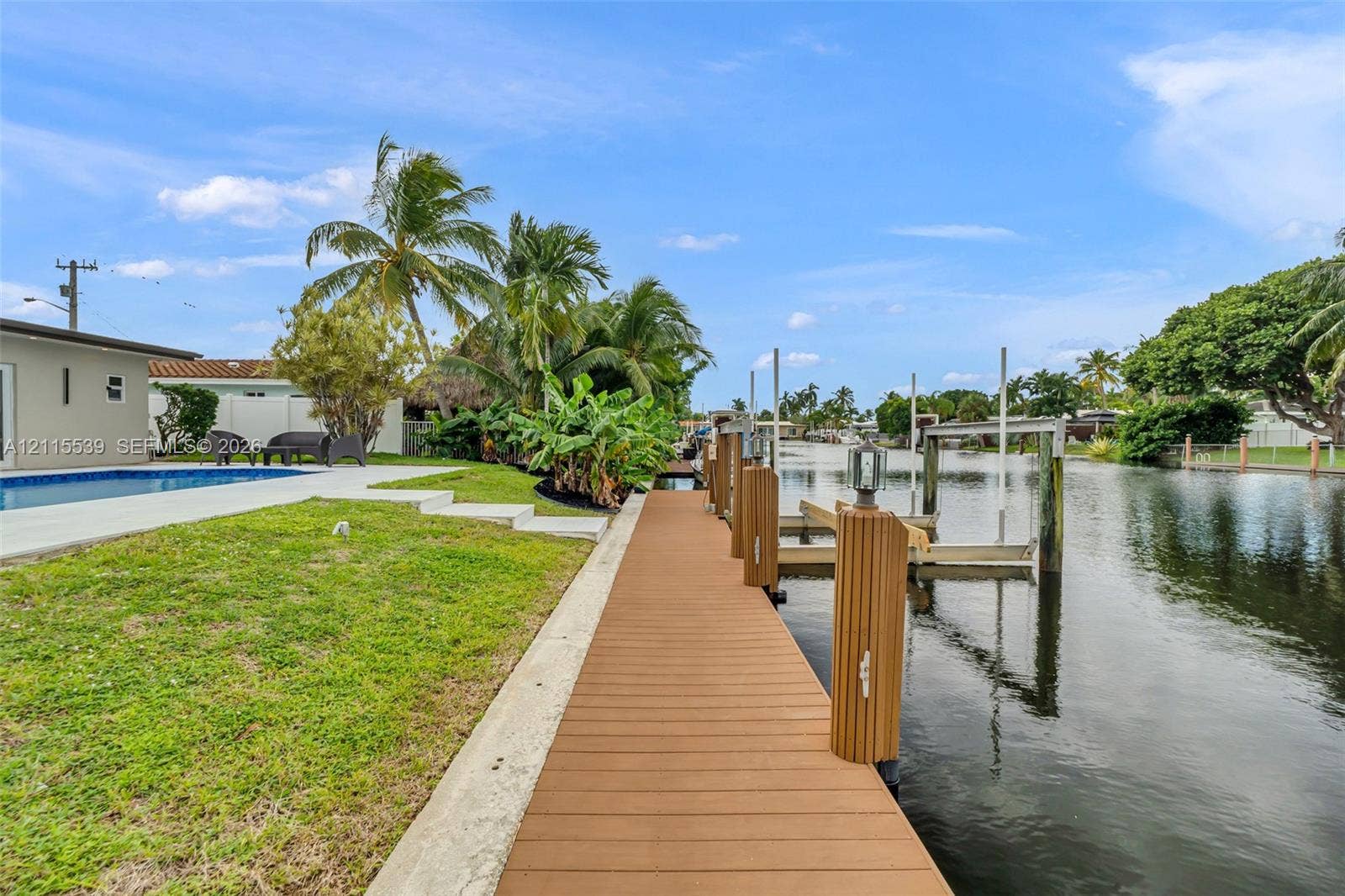 381 SE 6th Terrace, Pompano Beach, FL 33060 Waterfront property featuring a private dock with boat lift, composite decking, swimming pool, and concrete patio