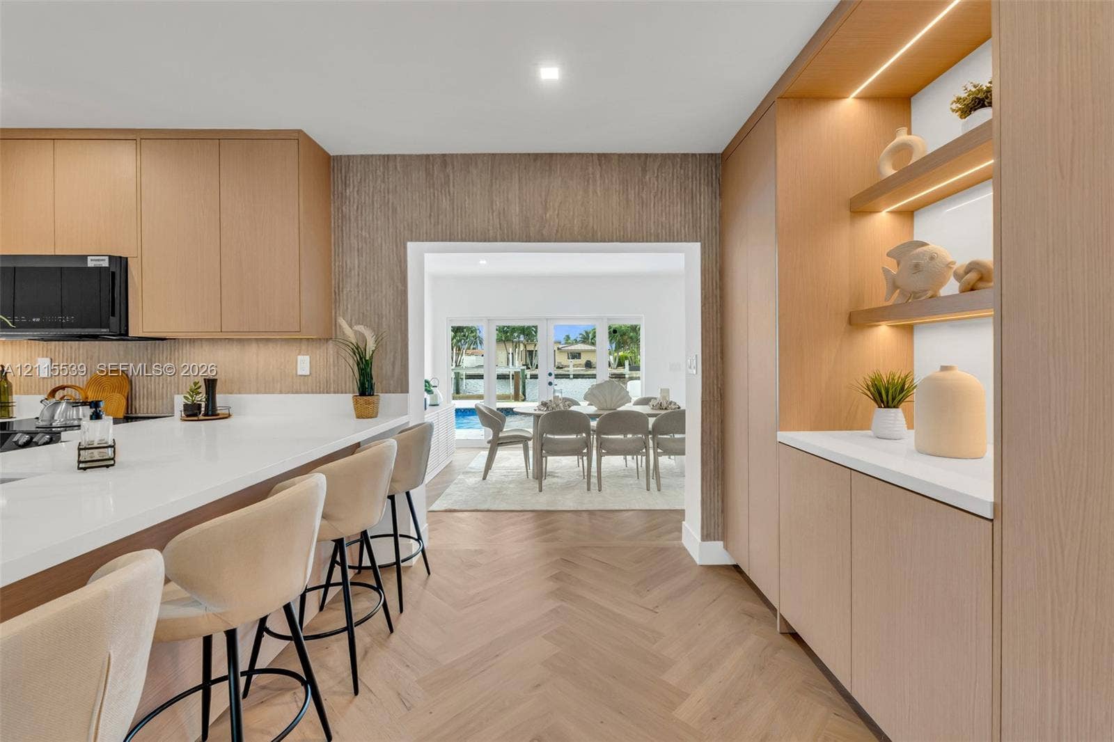 381 SE 6th Terrace, Pompano Beach, FL 33060 Kitchen featuring light wood cabinetry, white countertops, built-in display shelving with integrated lighting, and herringbone wood-finish flooring
