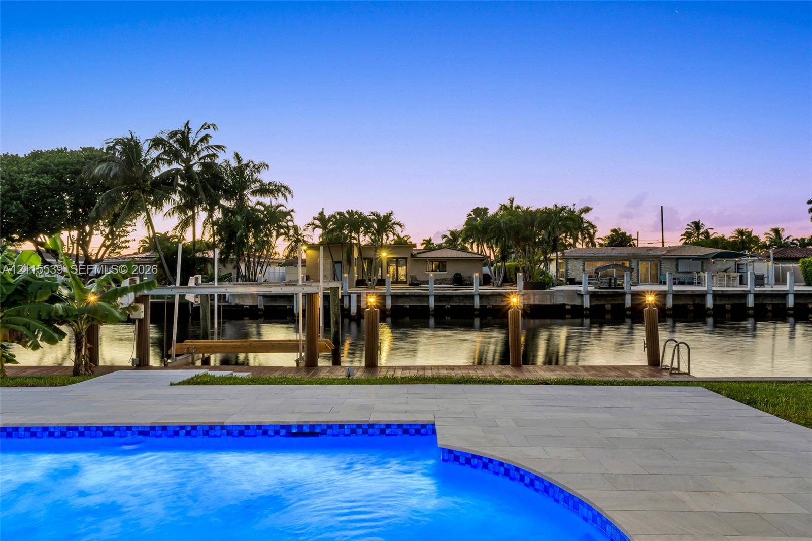 381 SE 6th Terrace, Pompano Beach, FL 33060 Waterfront property featuring a swimming pool with stone paver decking, a fixed wood dock, and nautical pilings