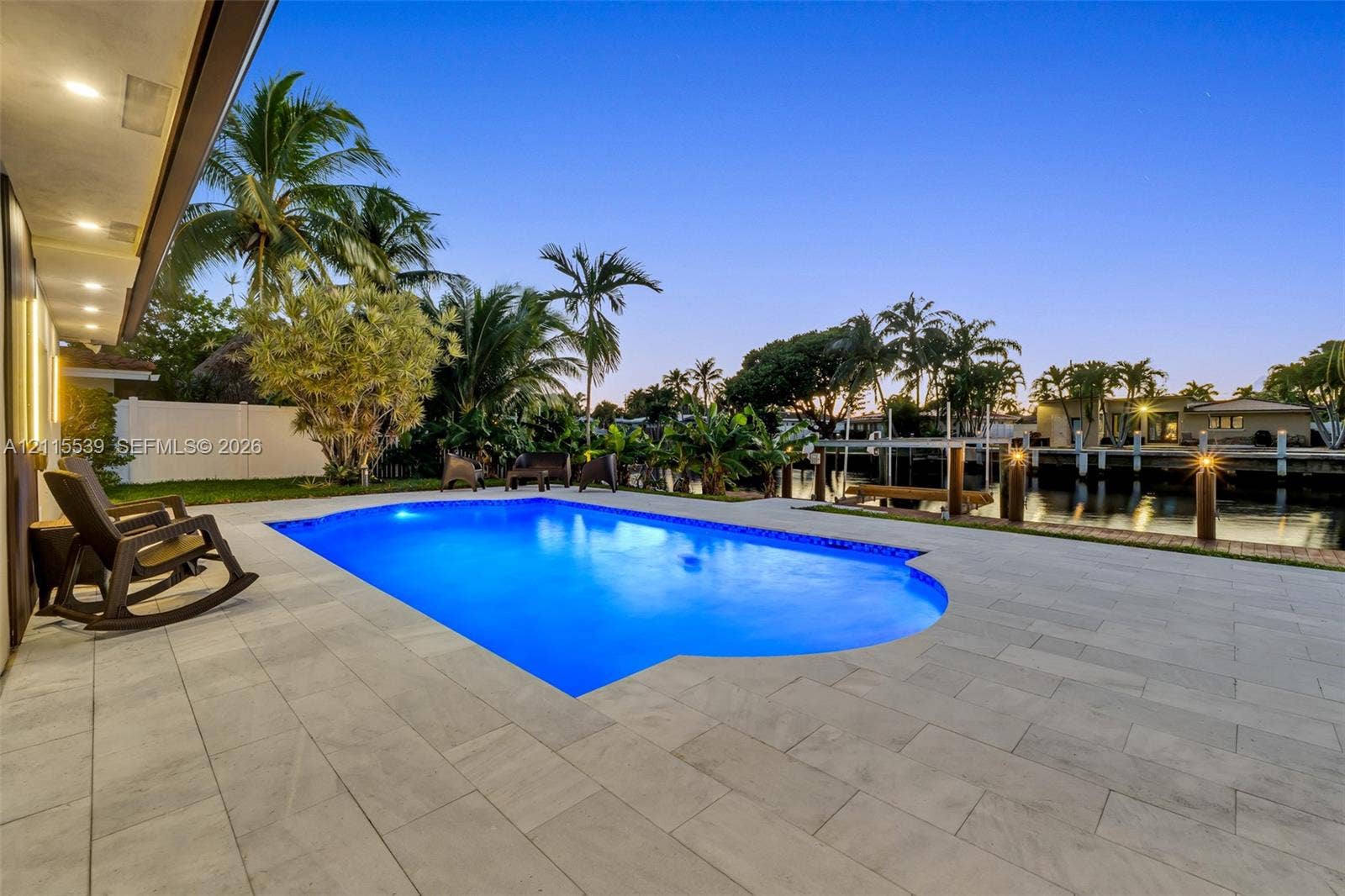 381 SE 6th Terrace, Pompano Beach, FL 33060 In-ground swimming pool featuring a large stone-paver deck, waterfront bulkhead, and tropical landscaping