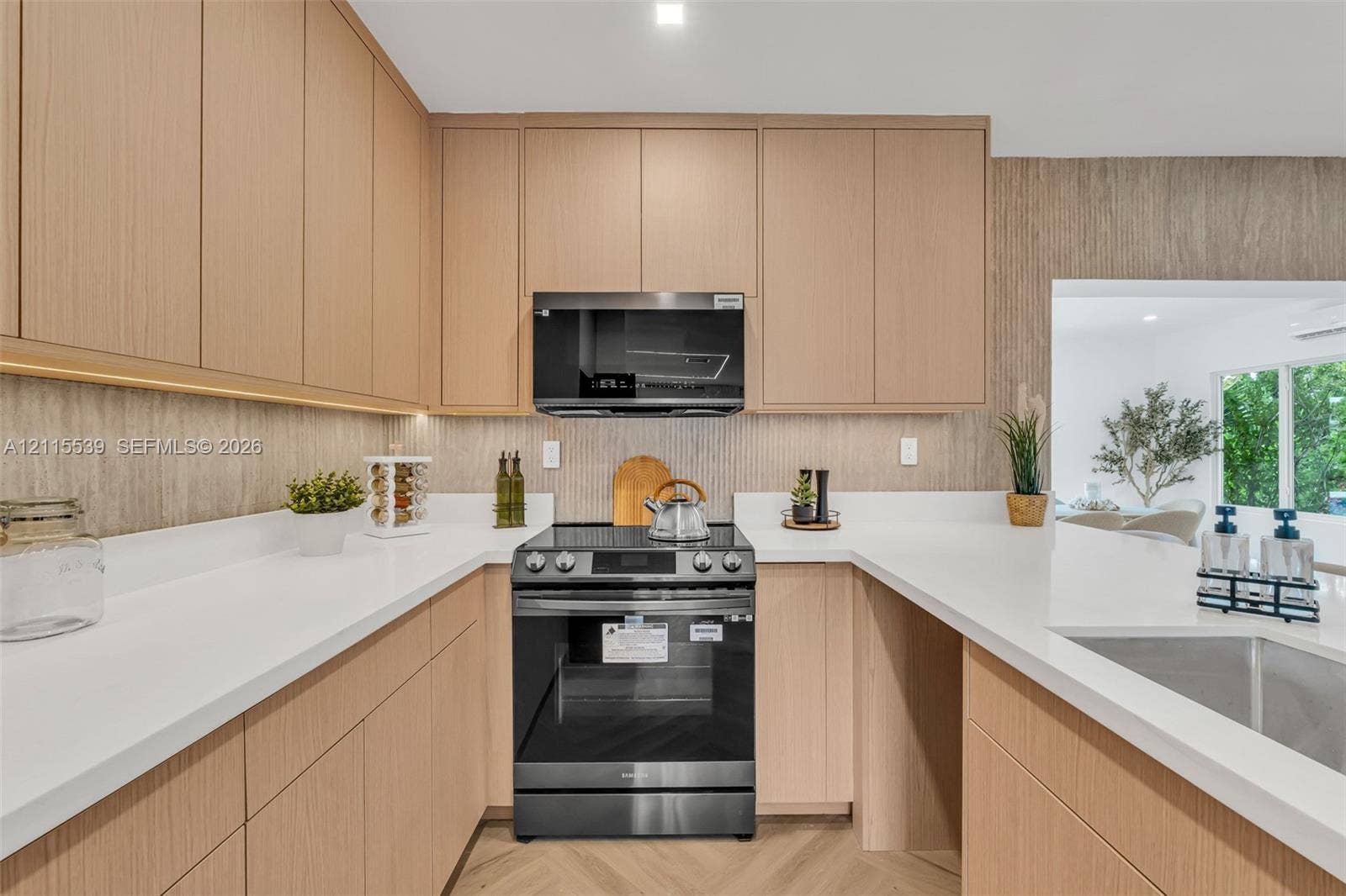 381 SE 6th Terrace, Pompano Beach, FL 33060 Kitchen featuring light wood-finish cabinetry, quartz countertops, vertical textured backsplash, stainless steel microwave, and chevron-patterned flooring