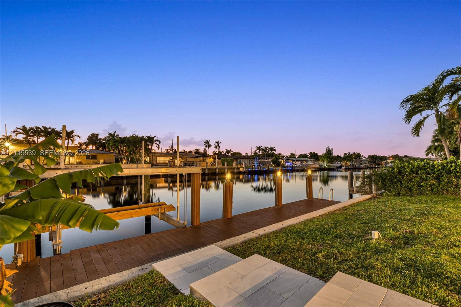 381 SE 6th Terrace, Pompano Beach, FL 33060 Waterfront property featuring a private dock, boat lift, manicured lawn, and stone paver walkway