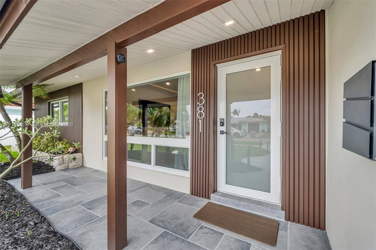 381 SE 6th Terrace, Pompano Beach, FL 33060 Two-car garage featuring a sectional overhead door, painted concrete flooring, white walls, and a dedicated exterior side-entry door