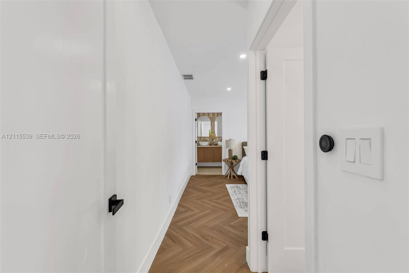 381 SE 6th Terrace, Pompano Beach, FL 33060 Hallway featuring wood-finish flooring in a herringbone pattern, matte black door hardware, and crisp white walls