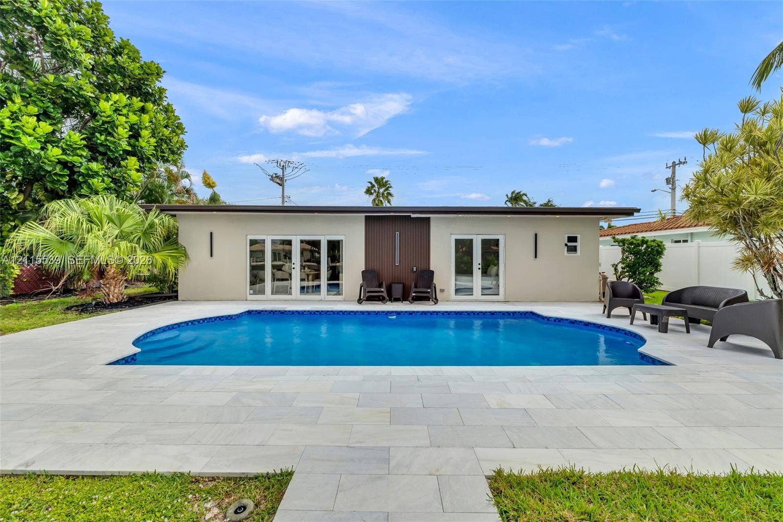 381 SE 6th Terrace, Pompano Beach, FL 33060 Backyard swimming pool featuring a light-toned stone deck, integrated stair entry, and dual sets of glass-paneled double doors