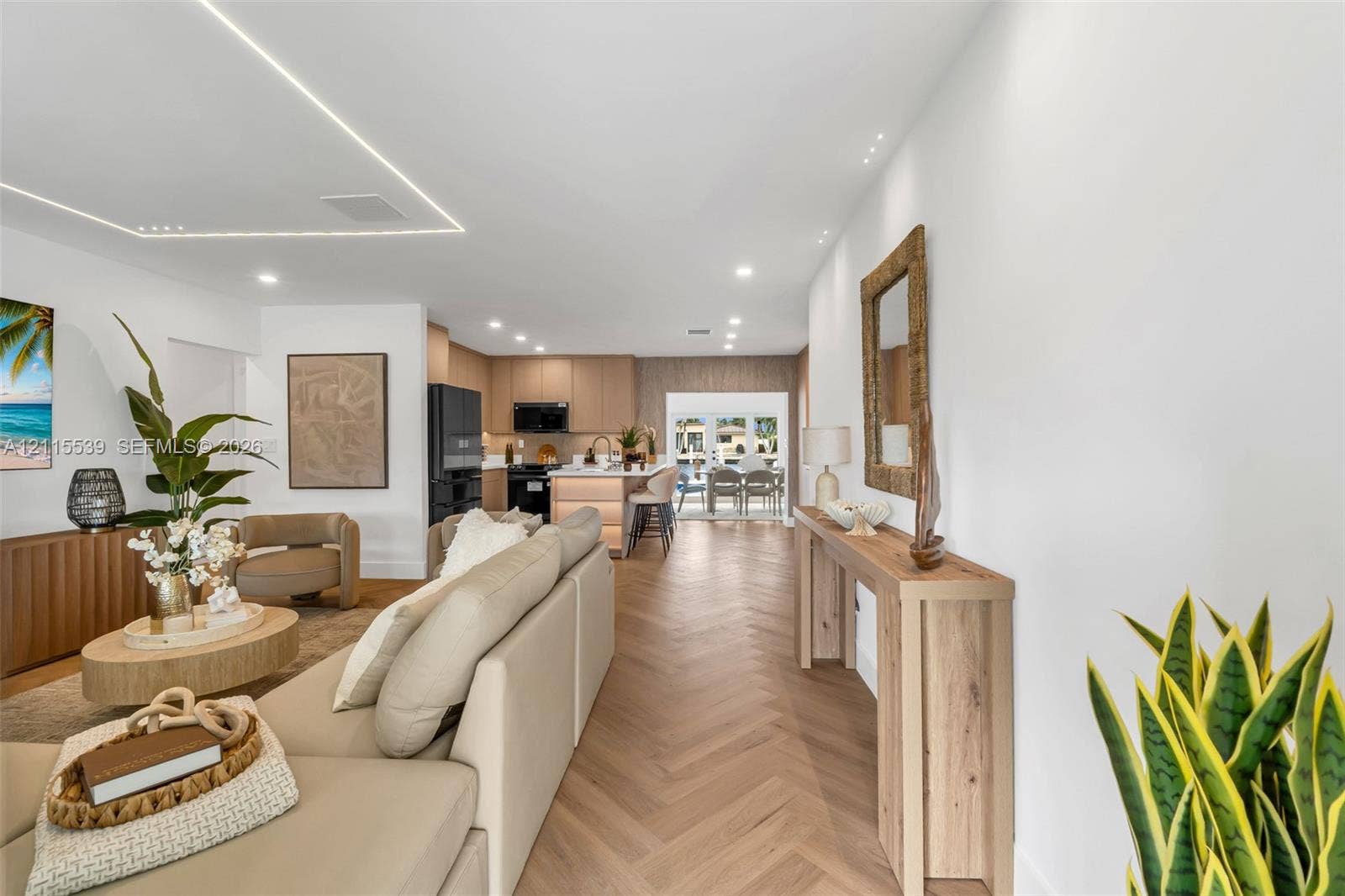 381 SE 6th Terrace, Pompano Beach, FL 33060 Herringbone wood-finish flooring, recessed ceiling lighting, linear architectural cove lighting, kitchen island with built-in cabinetry, and integrated black appliances