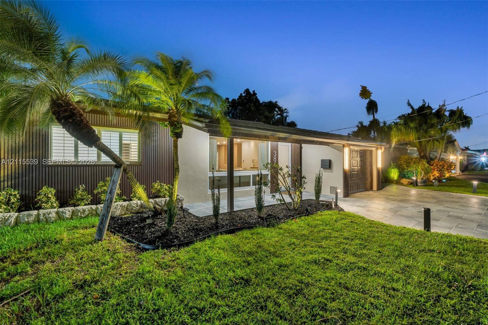 381 SE 6th Terrace, Pompano Beach, FL 33060 Single-story exterior featuring corrugated metal siding, stucco finish, stone landscape edging, and a paved driveway