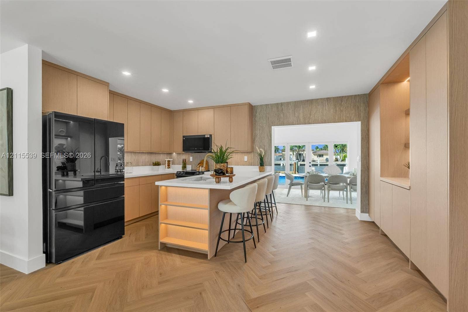 381 SE 6th Terrace, Pompano Beach, FL 33060 Kitchen featuring custom light wood cabinetry, white stone countertops, herringbone patterned wood-finish flooring, recessed lighting, and a center island with integrated under-counter illumination