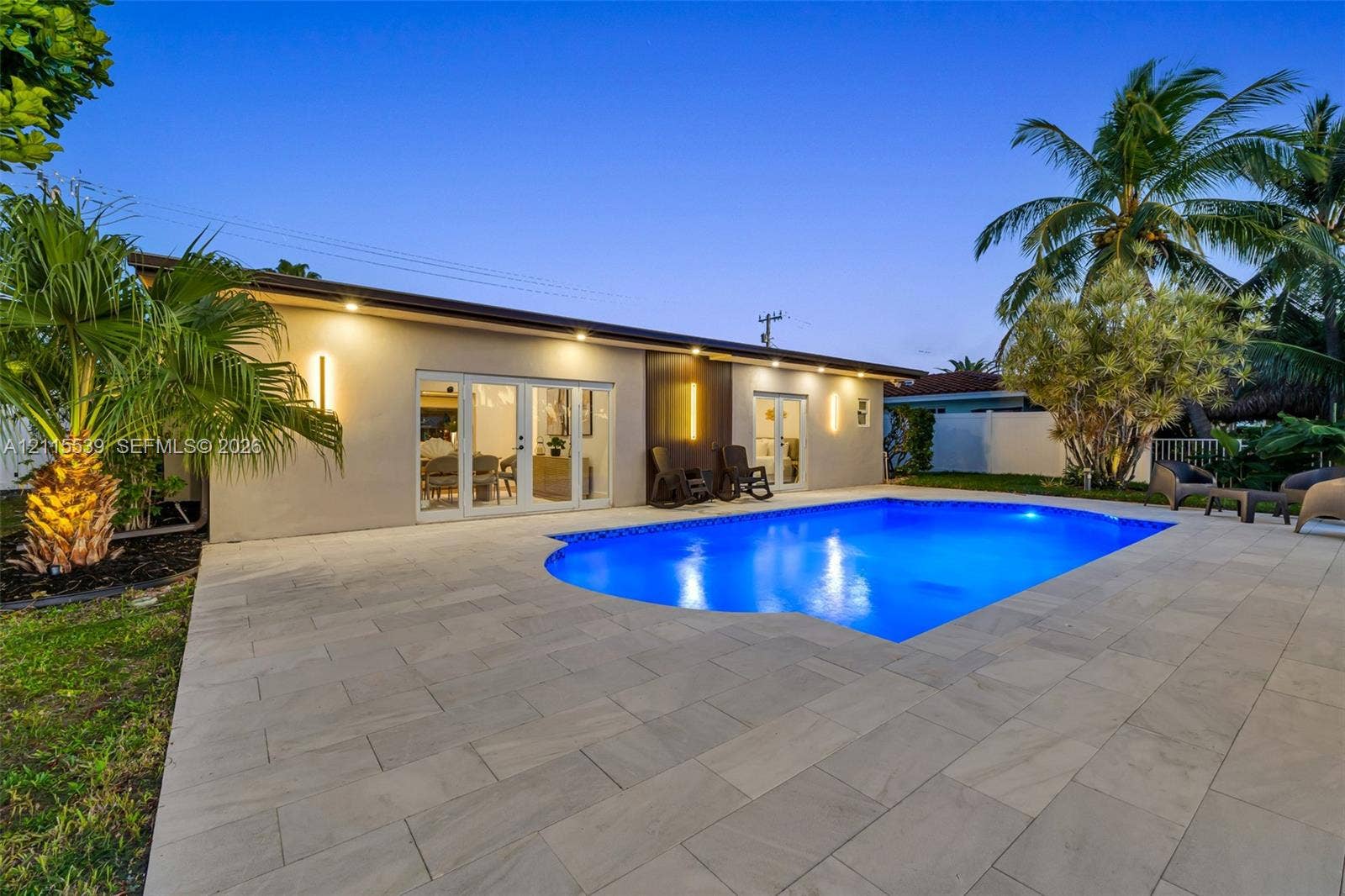 381 SE 6th Terrace, Pompano Beach, FL 33060 Outdoor space featuring a swimming pool, large-format paver patio, double French doors, and exterior wall-mounted accent lighting