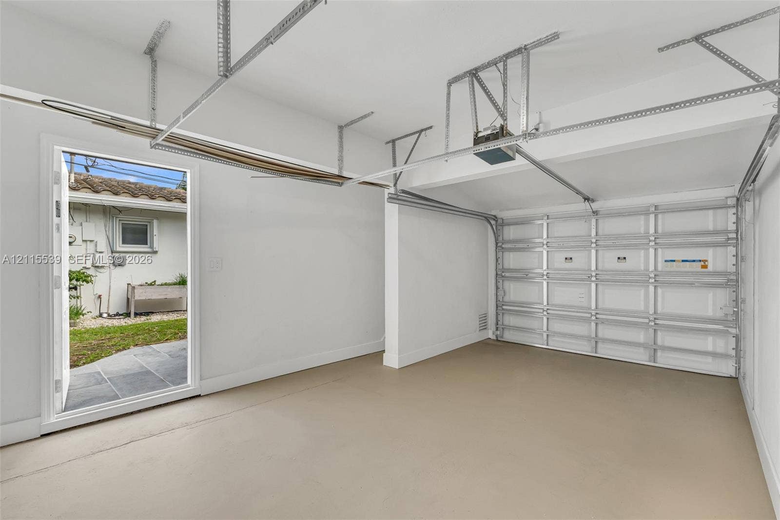 381 SE 6th Terrace, Pompano Beach, FL 33060 Two-car garage featuring a sectional overhead door, painted concrete flooring, white walls, and a dedicated exterior side-entry door