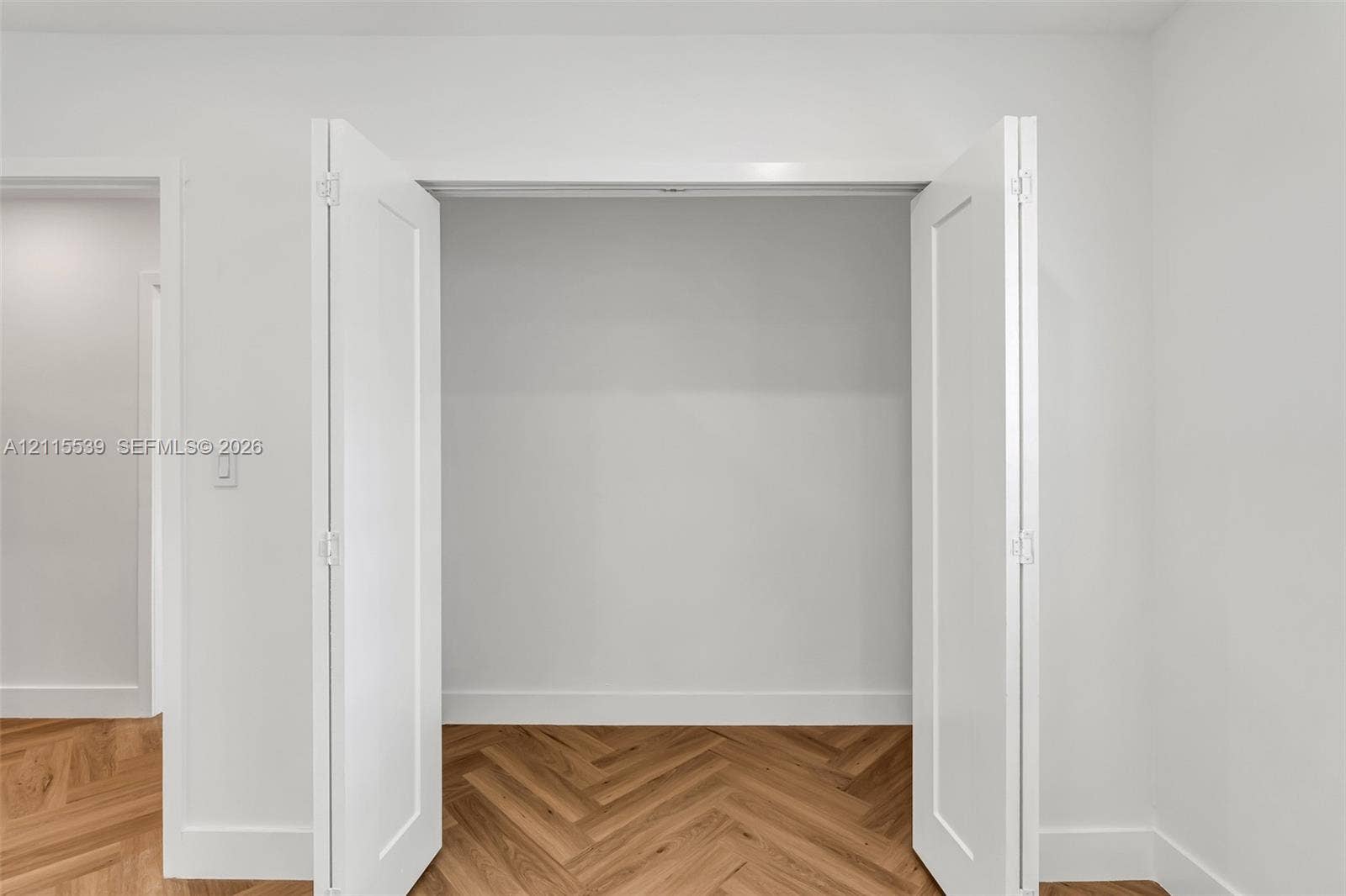 381 SE 6th Terrace, Pompano Beach, FL 33060 White bi-fold closet doors featuring a two-panel design and wood-finish herringbone flooring