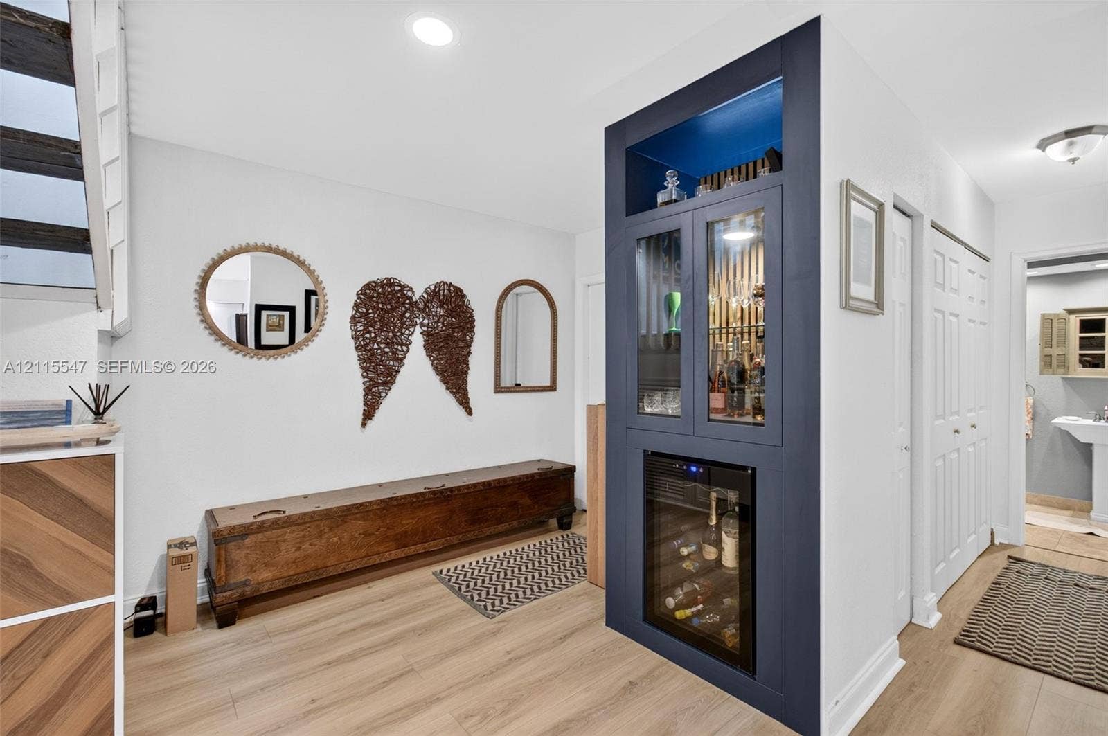 22862 Ironwedge Drive, #0, Boca Raton, FL 33433 Built-in dark navy cabinetry featuring glass-front display shelving, recessed lighting, and an integrated beverage refrigerator, complemented by wood-finish flooring and recessed ceiling lighting