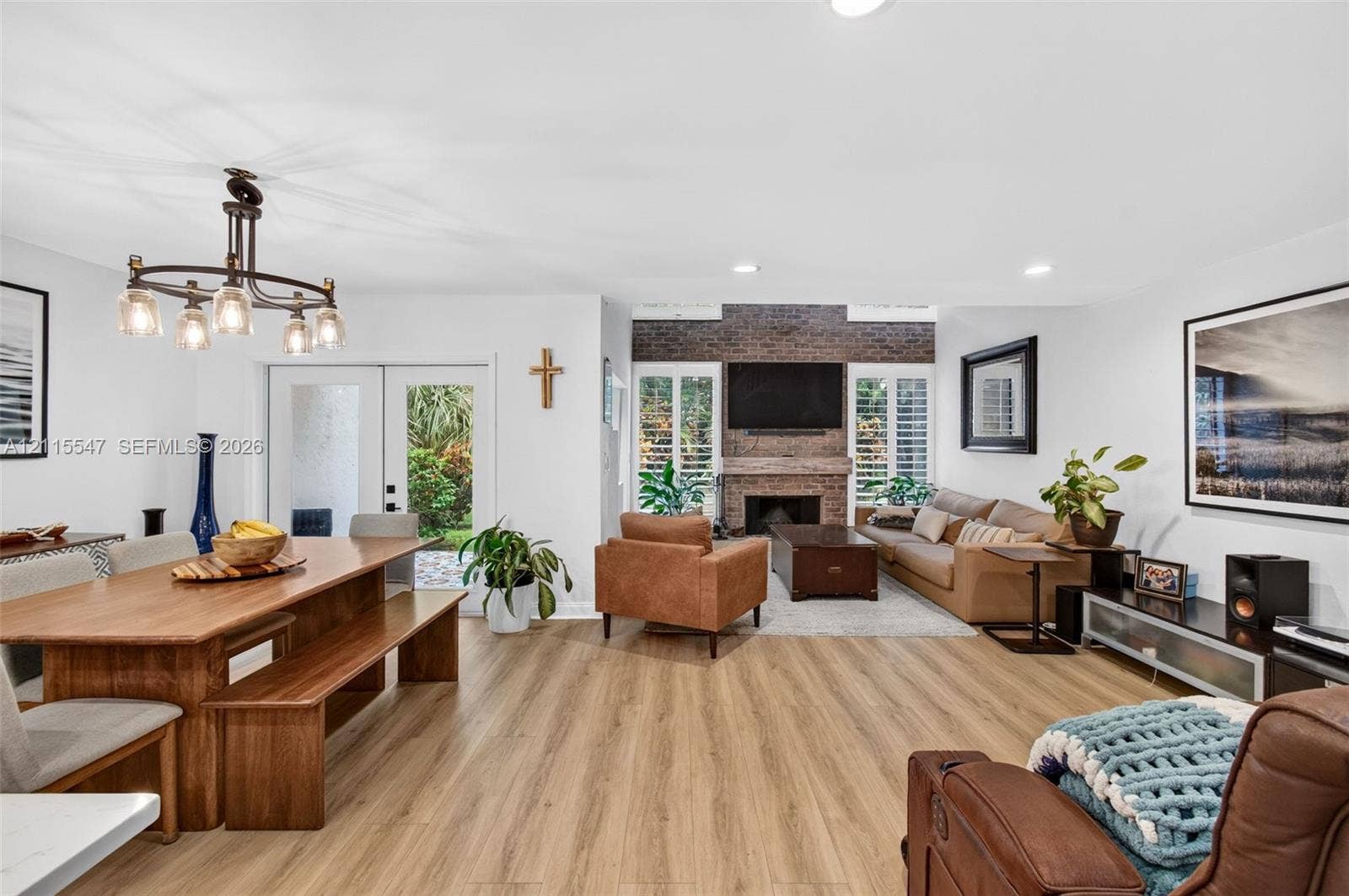 22862 Ironwedge Drive, #0, Boca Raton, FL 33433 Open-concept interior featuring wood-finish flooring, a full-height brick fireplace, recessed lighting, a multi-arm chandelier, and plantation shutters