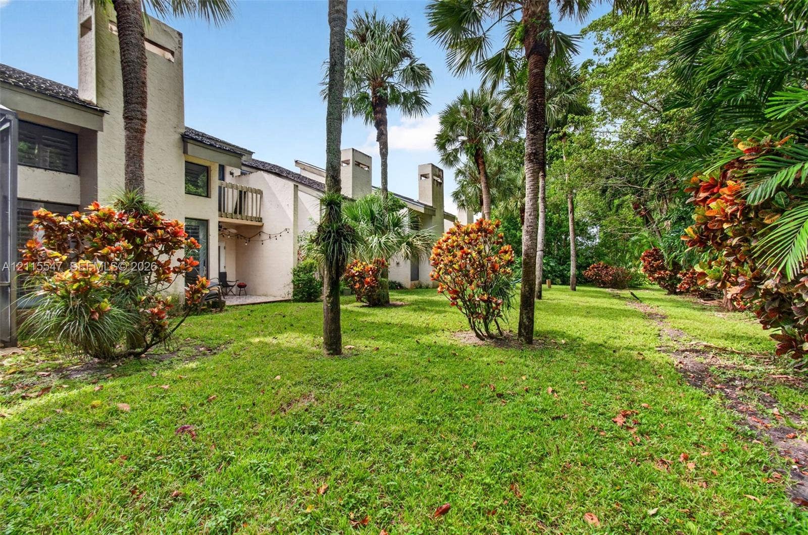 22862 Ironwedge Drive, #0, Boca Raton, FL 33433 Stucco exterior featuring multiple chimney stacks, a second-story wooden balcony, and established palm trees within a landscaped grounds area
