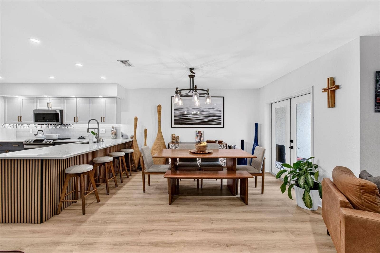 22862 Ironwedge Drive, #0, Boca Raton, FL 33433 Open-concept kitchen and dining area featuring wood-finish flooring, a kitchen island with vertical wood-slat detailing, quartz countertops, recessed lighting, and double glass doors