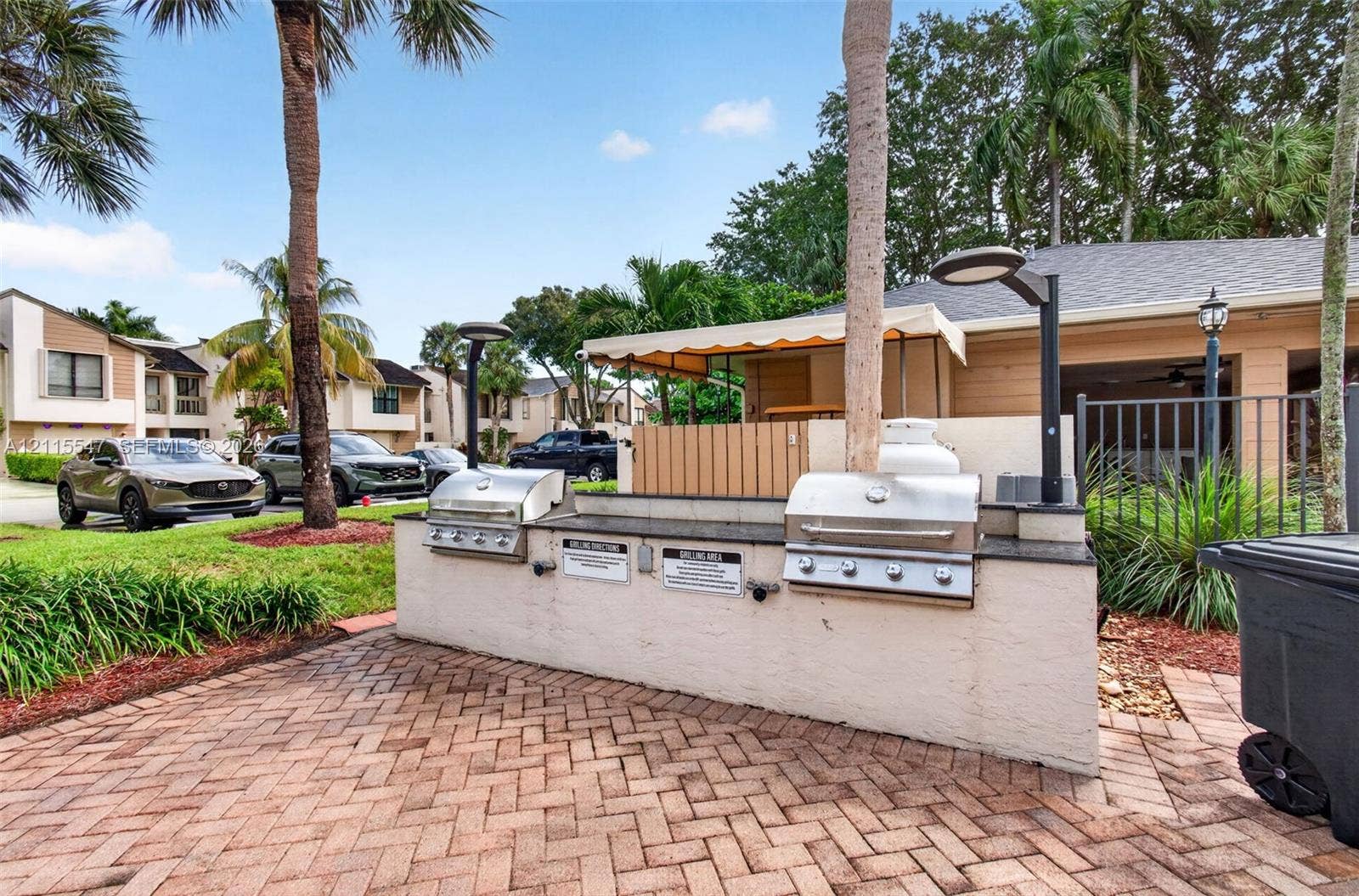 22862 Ironwedge Drive, #0, Boca Raton, FL 33433 Outdoor grilling station featuring dual stainless steel built-in grills, stone countertop, brick-paver flooring, and integrated lighting