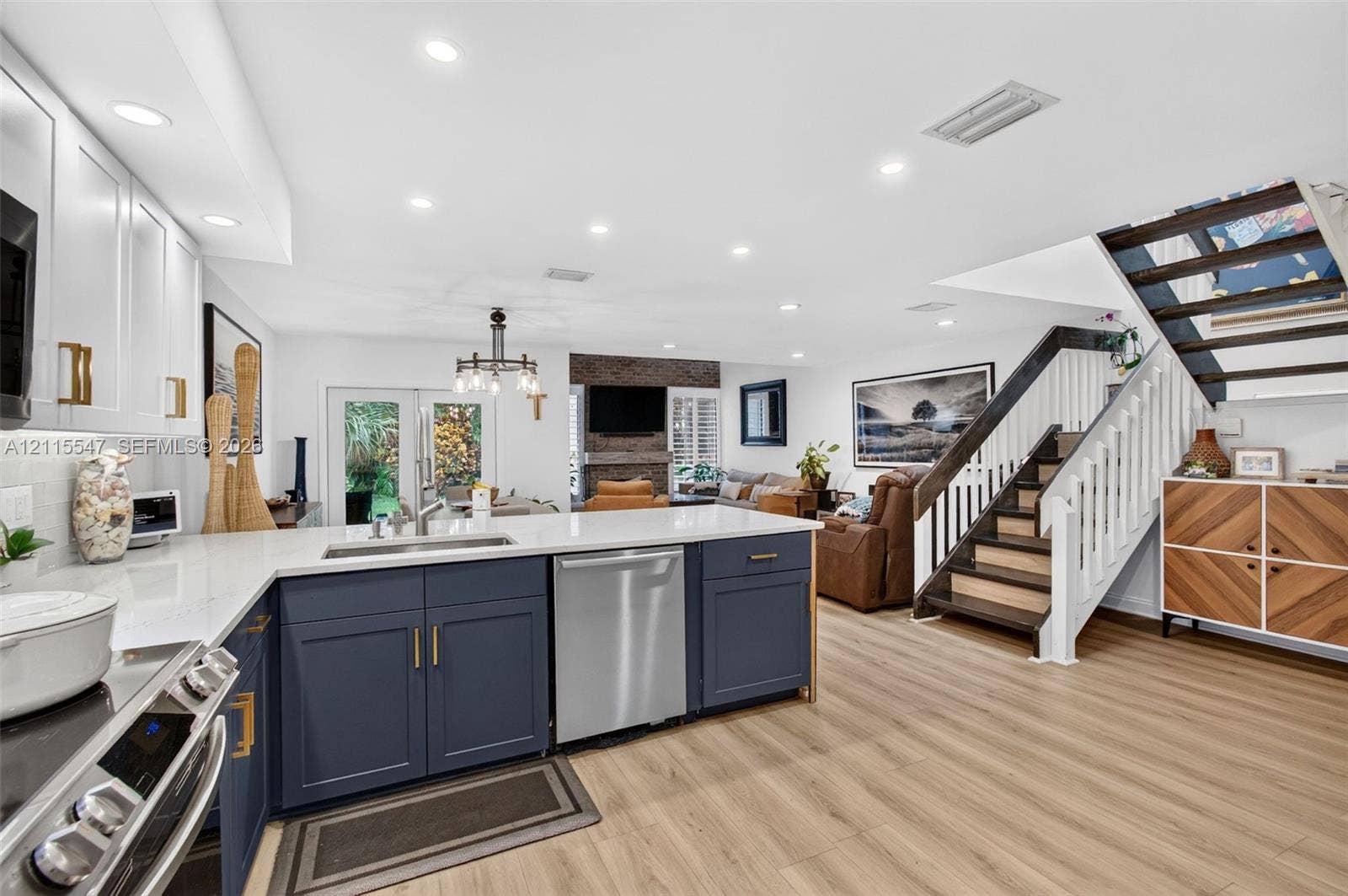 22862 Ironwedge Drive, #0, Boca Raton, FL 33433 Kitchen featuring navy cabinetry, quartz countertops, stainless steel appliances, wood-finish flooring, and a staircase with a white balustrade