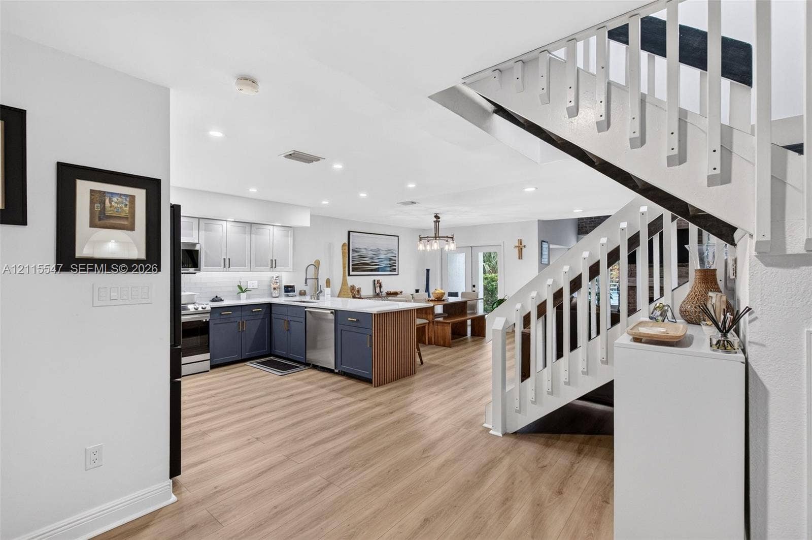 22862 Ironwedge Drive, #0, Boca Raton, FL 33433 Kitchen featuring two-tone cabinetry, wood-finish flooring, recessed lighting, and a staircase with a white balustrade