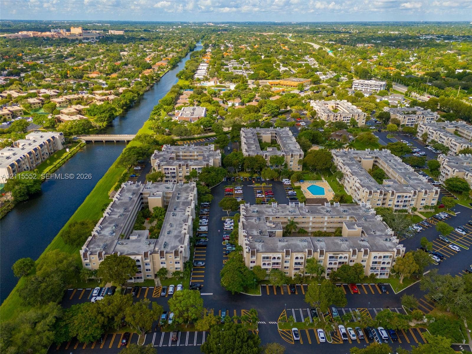7805 Camino Real, #H-220, Miami, FL 33143 Aerial perspective of a multi-building residential complex featuring a swimming pool, surface parking, and canal frontage with mature landscaping