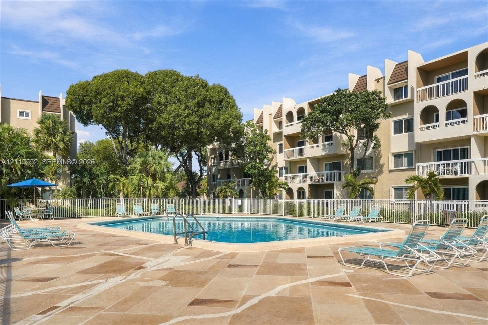 7805 Camino Real, #H-220, Miami, FL 33143 In-ground swimming pool featuring a concrete deck, perimeter fencing, and mature landscaping