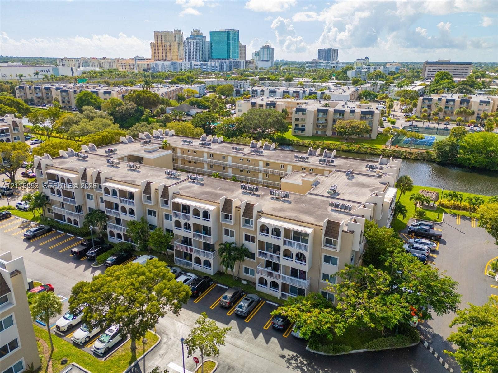 7805 Camino Real, #H-220, Miami, FL 33143 Multi-story residential complex featuring arched architectural detailing, private balconies, on-site surface parking, and waterfront grounds