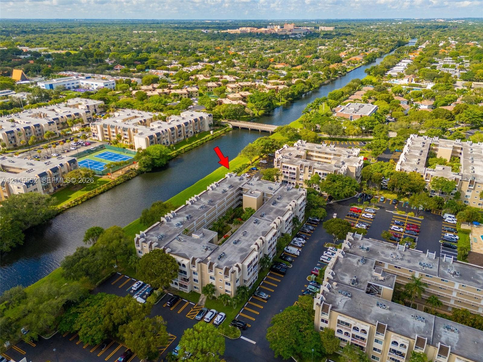 7805 Camino Real, #H-220, Miami, FL 33143 Aerial perspective of multi-story residential building featuring water frontage, dedicated surface parking, and exterior landscaping