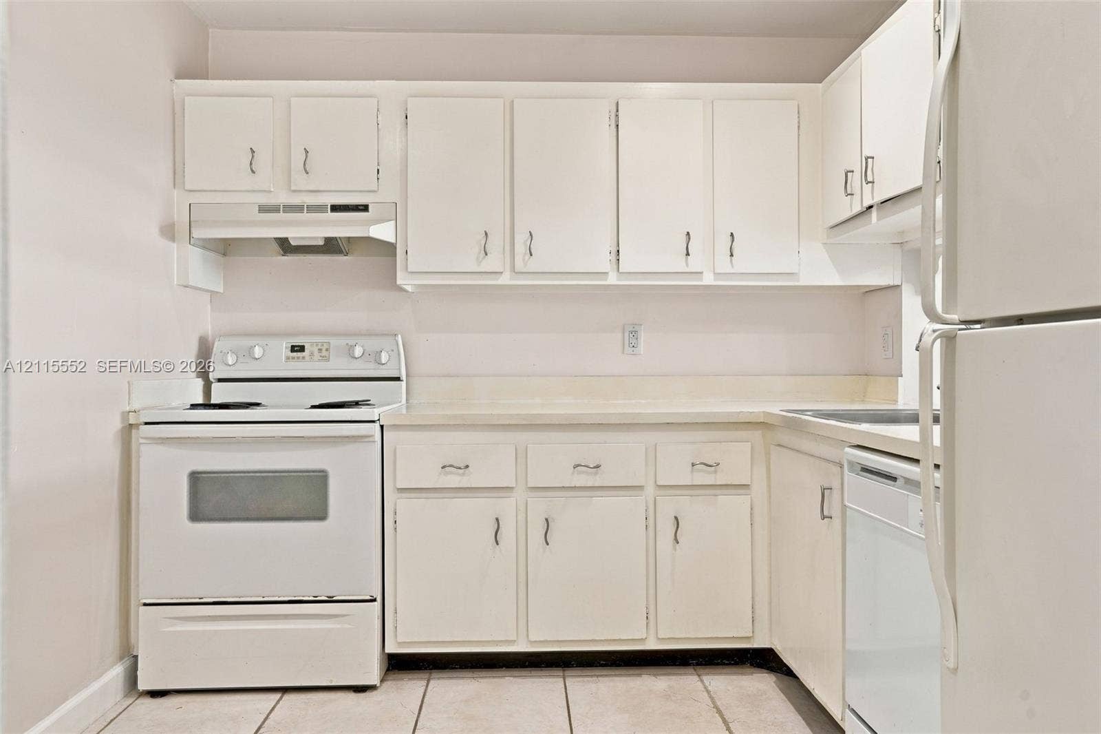 7805 Camino Real, #H-220, Miami, FL 33143 Kitchen featuring white cabinetry, a neutral solid-surface countertop, tiled flooring, and integrated white appliances including a range, range hood, and dishwasher